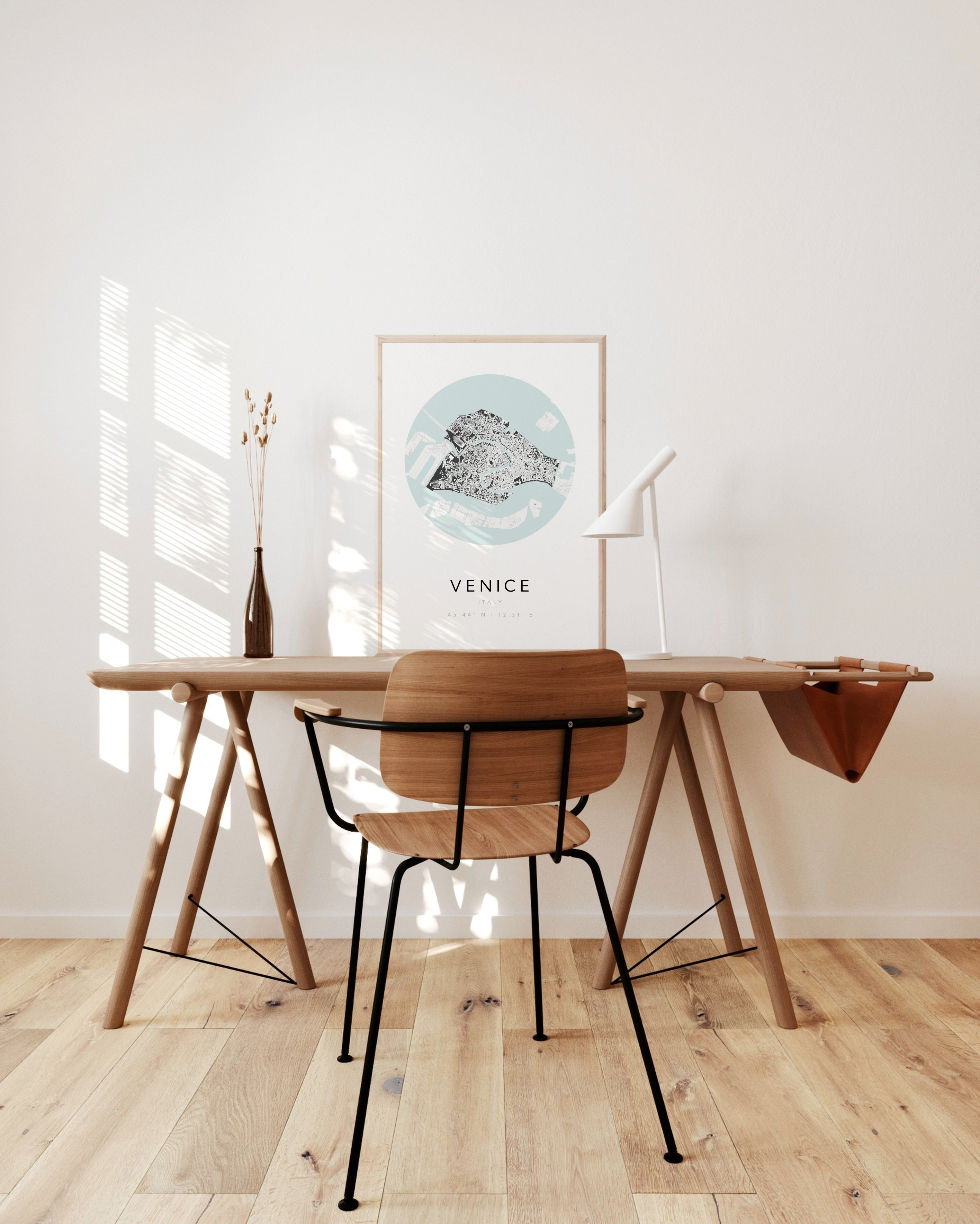 A Venice poster sitting on top of a wooden desk placed against a white wall.